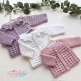 Crocheted cardigans on hanger with greenery