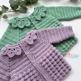 Two crocheted baby outfits, one green and one purple, on a white background with greenery.