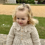 Young girl wearing a crocheted beige cardigan outdoors