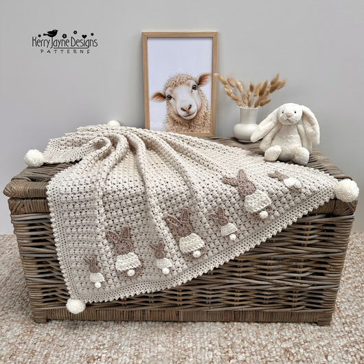A beige crochet blanket with bunny appliques added