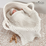 A baby in a basket with a christmas tree blanket draped over the baby, a crochet blanket pattern by Kerry Jayne Designs 