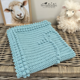A folded goose blanket on a wicker trunk in a nursery 