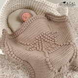 baby in a moses basket with a highland cow blanket draped over the baby