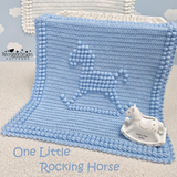 Blue crochted blanket with a rocking horse design and a small rocking horse toy on a light background.