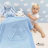 Baby sitting with a blue Rocking Horse blanket and plush toys against a blue wall with cloud patterns.