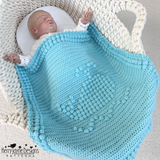 Turquoise whale blanket on baby in crib
