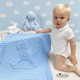 Baby sitting next to a rocking horse blanket 