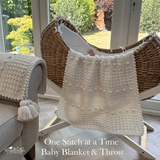 Baby blanket and throw draped over a crib with a garden view outside
