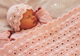 Baby under a pink blanker and hat