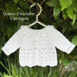White crochet cardigan on a hanger against a green leafy background