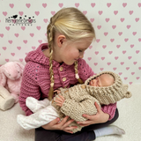 A child holding a doll dressed in hoodies 