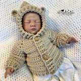 A Baby wearing a hooded crochet jacket