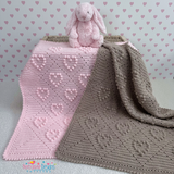 Pink and gray crocheted baby blankets with a pink stuffed bunny on a heart-patterned background.