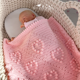 Baby doll in a basket with a pink knitted blanket, featuring Kerry Jayne Designs branding.