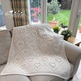 Crocheted blanket on a sofa with 'Kerry Jayne Designs' branding, in a home setting.