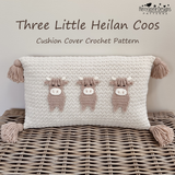 Crocheted rectangular cushion cover with three small cow motifs in beige and white, displayed on a woven wicker surface. Text at the top reads 'Three Little Heilan Coos' and 'Cushion Cover Crochet Pattern,' with the Kerry Jane Designs Patterns logo in the upper right.